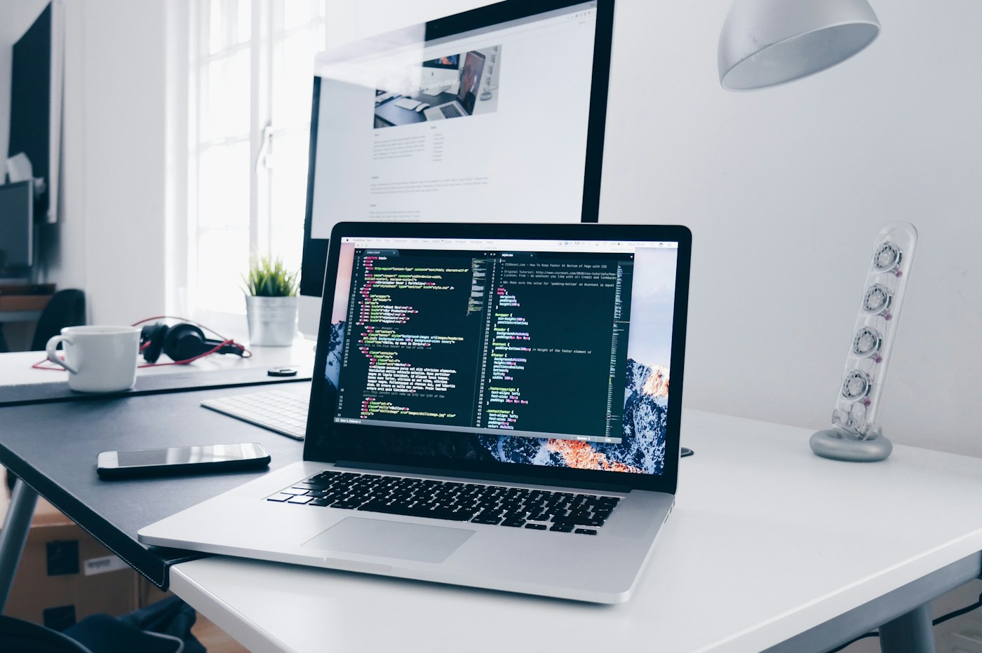 Laptop displaying software code on a development desk